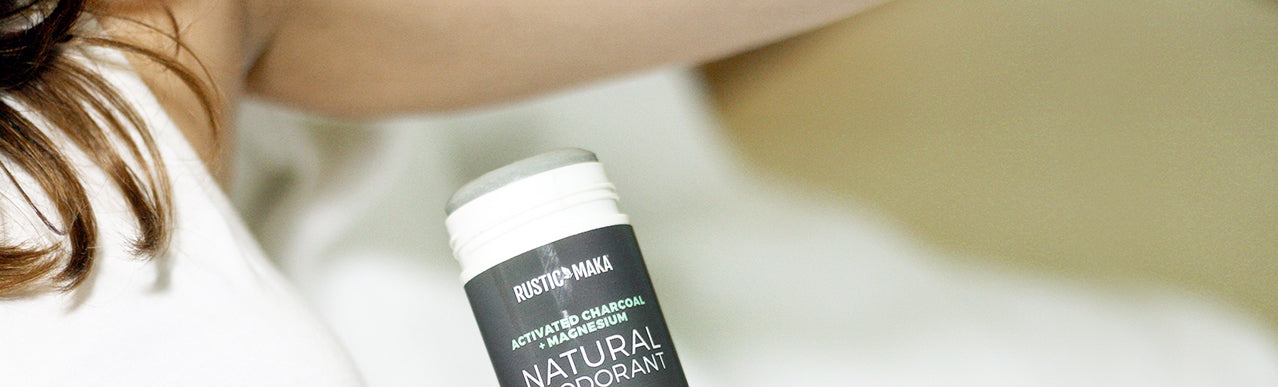 picture of a woman holding charcoal deodorant near her armpit