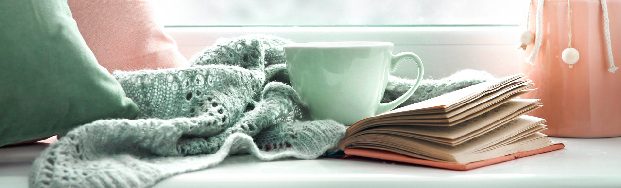 image of a cup, blanket and a book