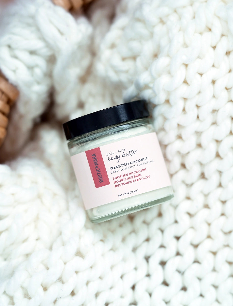 Jar of toasted coconut body butter on a textured white surface