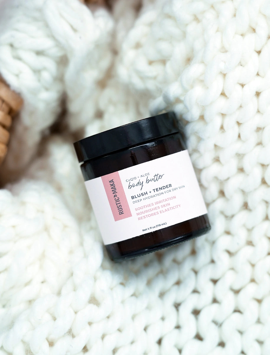 Jar of body butter labeled 'Blush + Tender' on a textured white surface