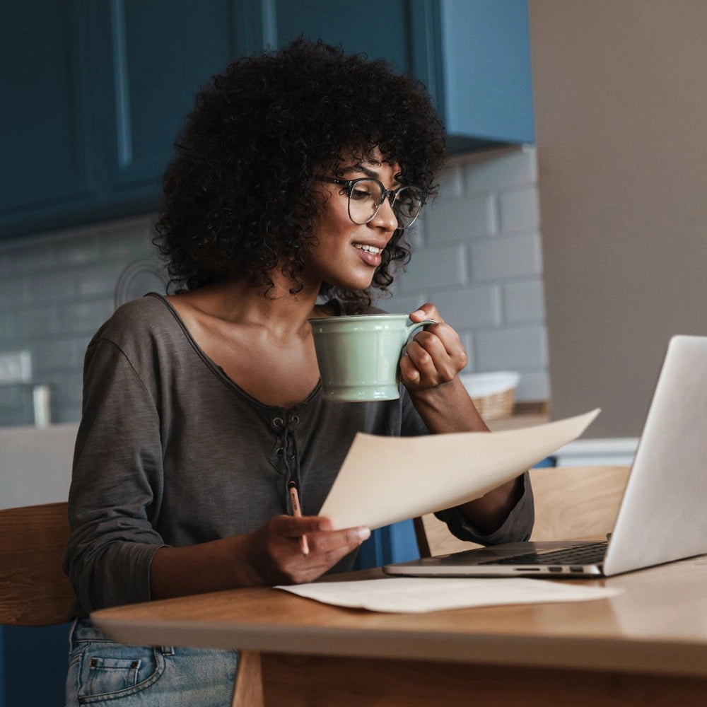 lady sitting with coffee and paperwork in the kitchen