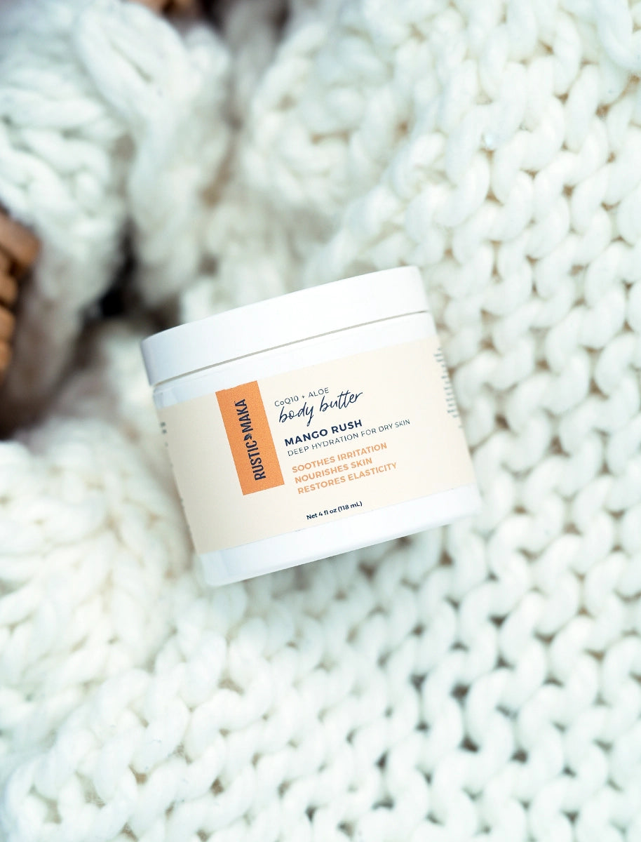 Body butter container labeled 'Mango Rush' on a textured white surface