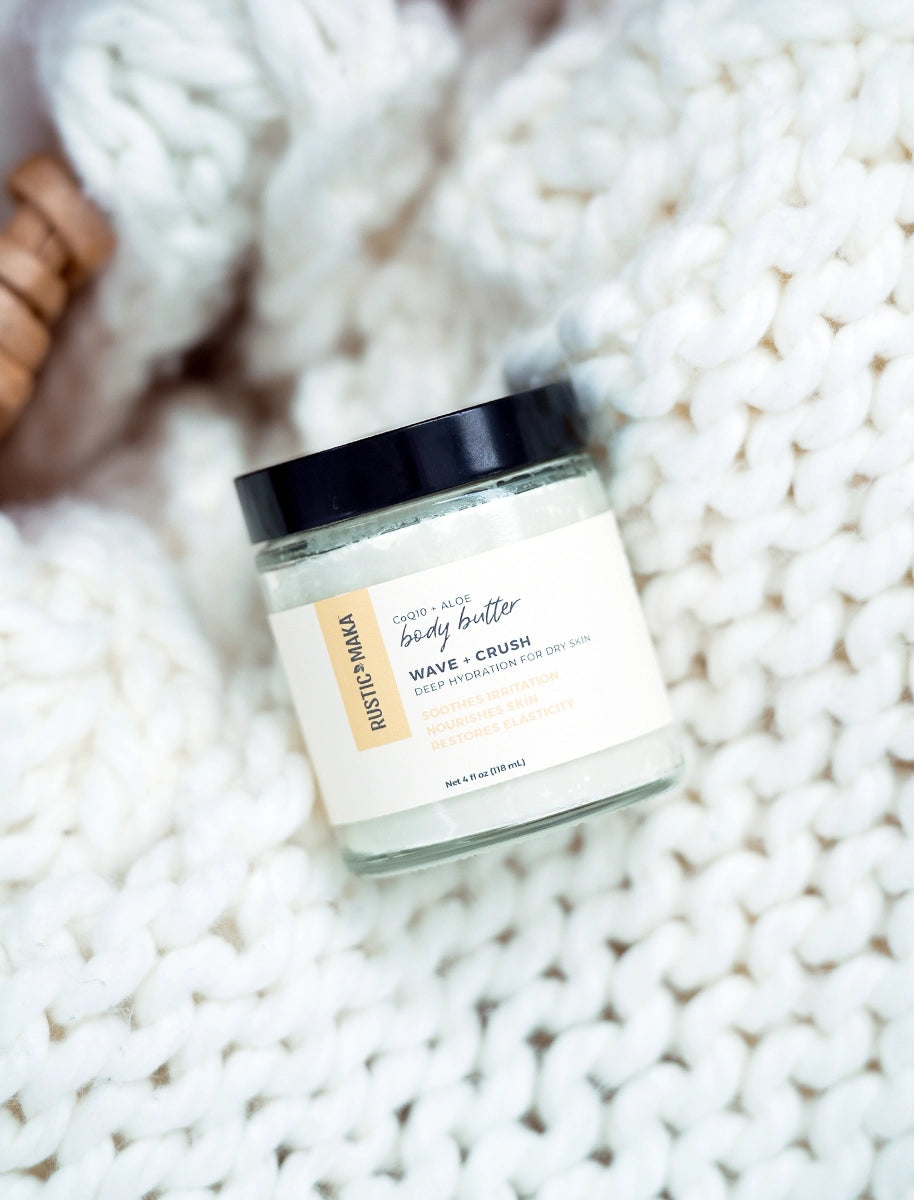 Jar of body butter labeled 'Wave Crush' on a textured white surface